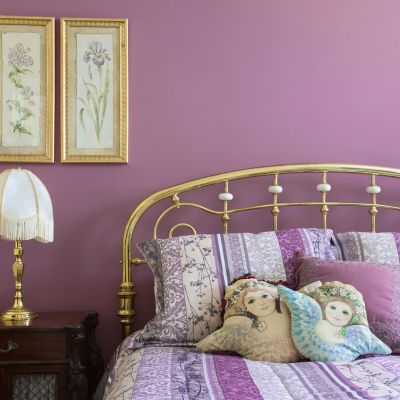 Lavender bedroom interior with brass furnishings and headboard