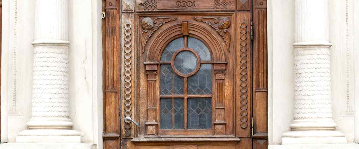 7. Panelled Wooden Jali Door Design with a Glass Insert