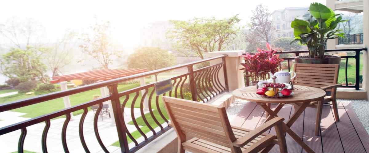A simple balcony decoration with a couple of wooden chairs and a table. 