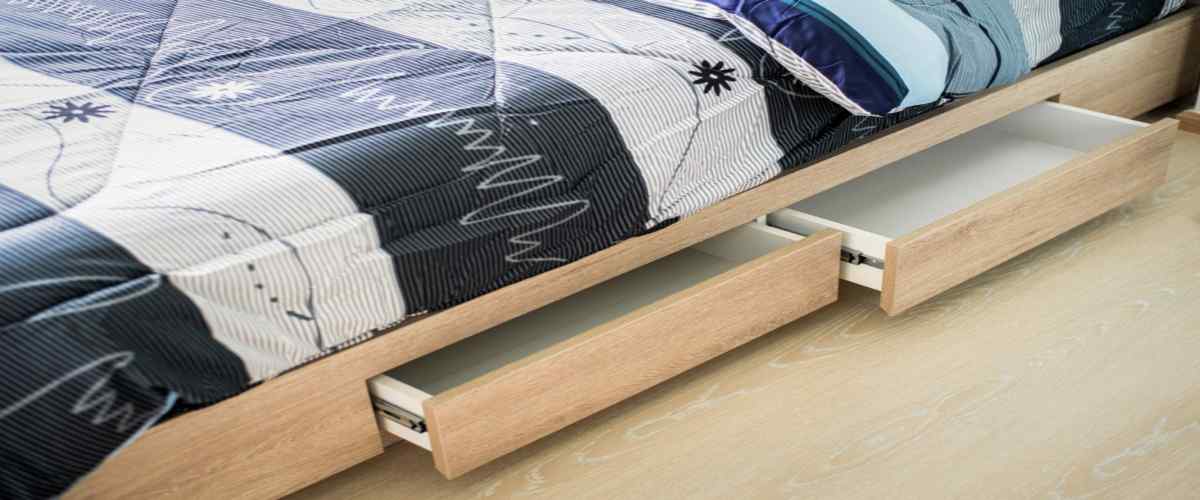 opened drawer under the modern bed in a small bedroom